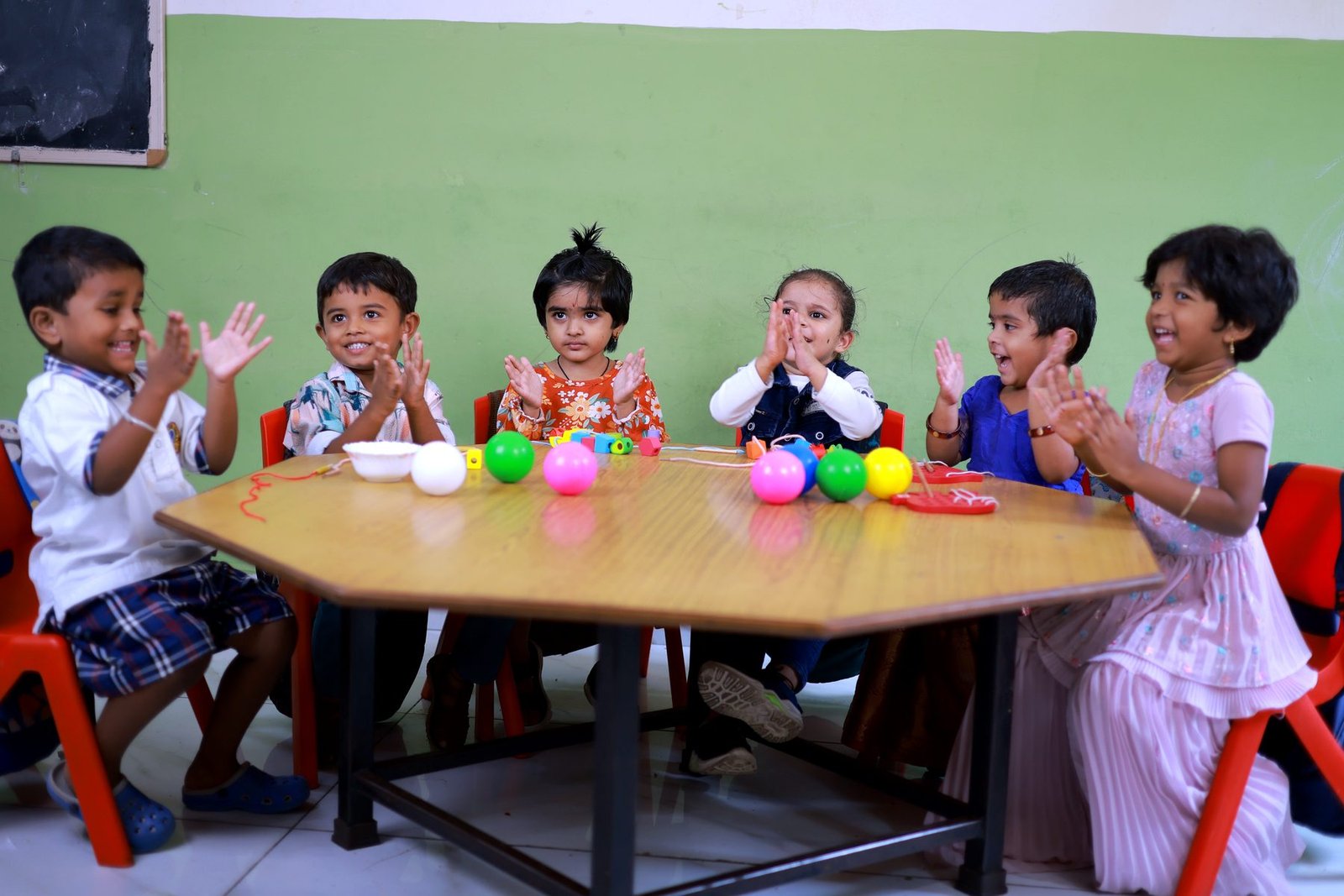 Preschool children clapping at an activity table